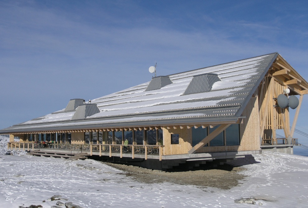 External view of Chäserrugg mountain inn with snow on the roof and snow-covered ground.