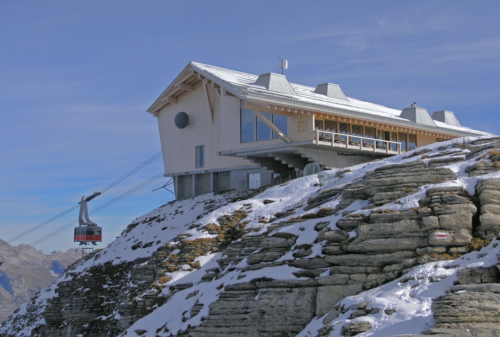 External view of Chäserrugg mountain inn with the cable car and rocks in the foreground.