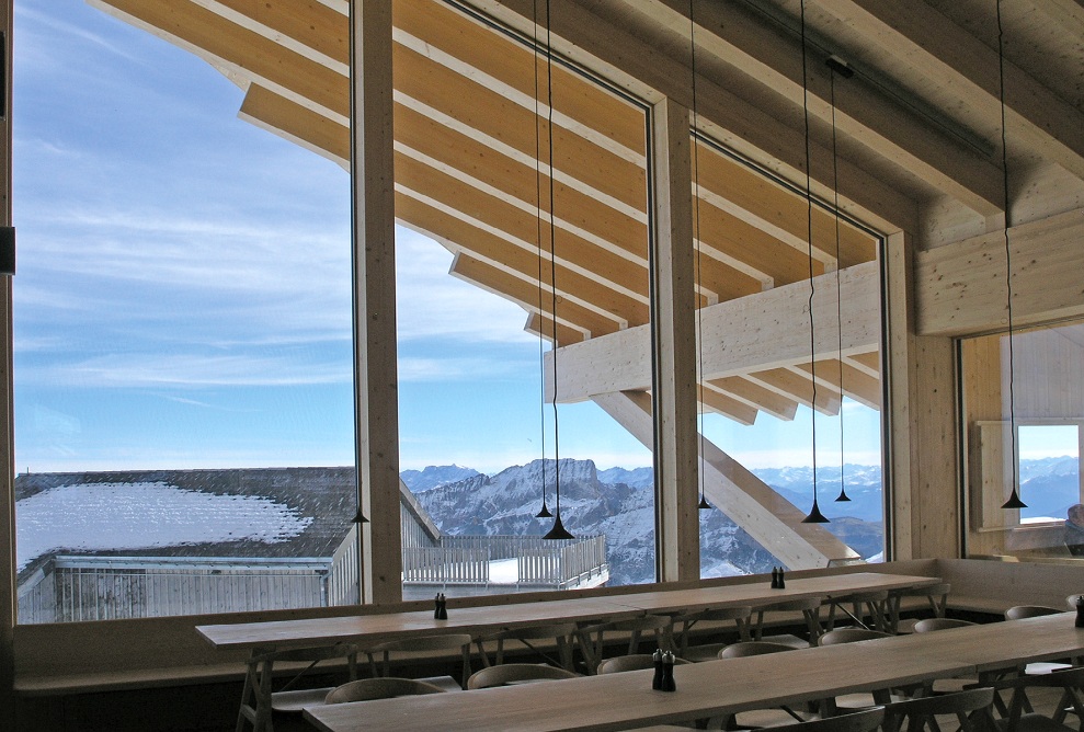 Espace de restauration de l’auberge de montagne de Chäserrugg avec tables et chaises, et vue panoramique sur les montagnes sous un ciel bleu