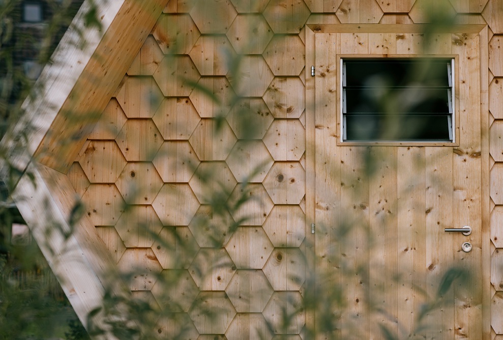 Detailed view of the wooden entrance door and facade with honeycomb wood shingles 