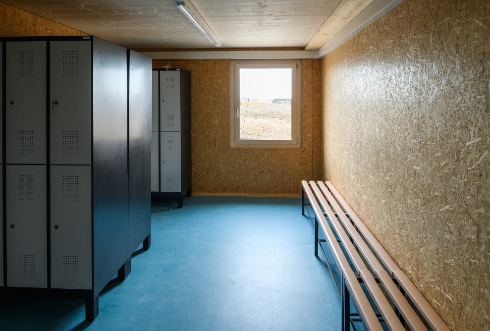 View of the cloakroom for Bio-Bäckerei Lehmann personnel. Interior finishing with cloakroom lockers and benches for changing. Blue flooring.