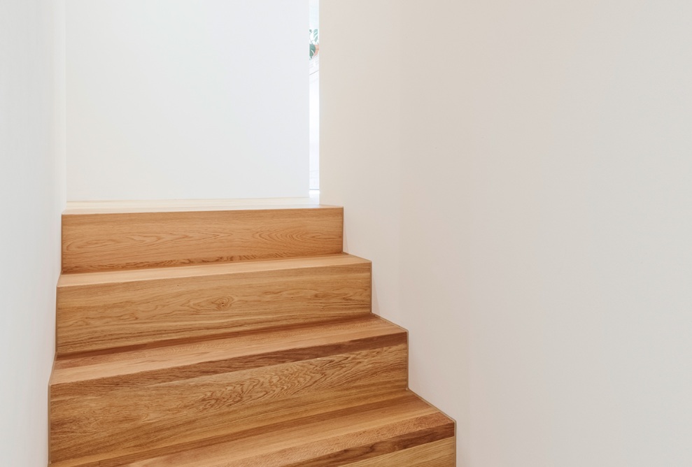 White interior walls in the hallway with wooden stairs.