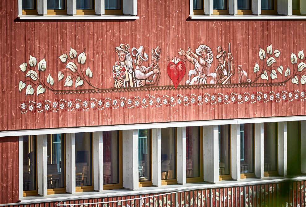 Red-brown wooden facade of the Dorfhus Gupf with paintings
