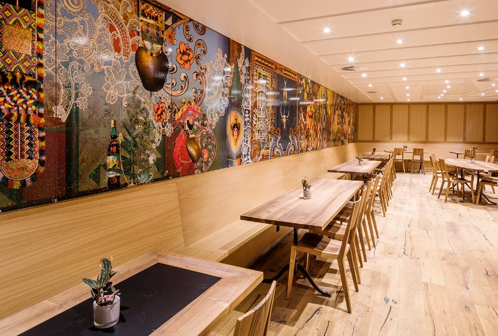 Salle à manger de l’hôtel Säntis avec des meubles en bois. Les murs sont décorés de motifs traditionnels suisses.