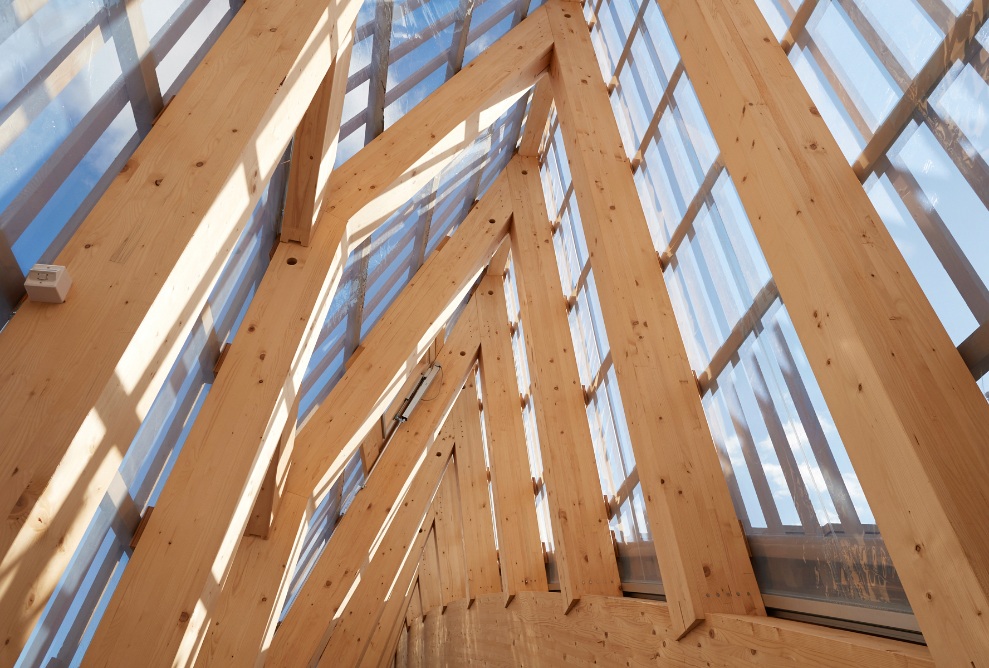Vue détaillée de la structure du toit en poutres de bois, qui sont recouvertes de vitres et laissent ainsi entrer beaucoup de lumière dans le bâtiment