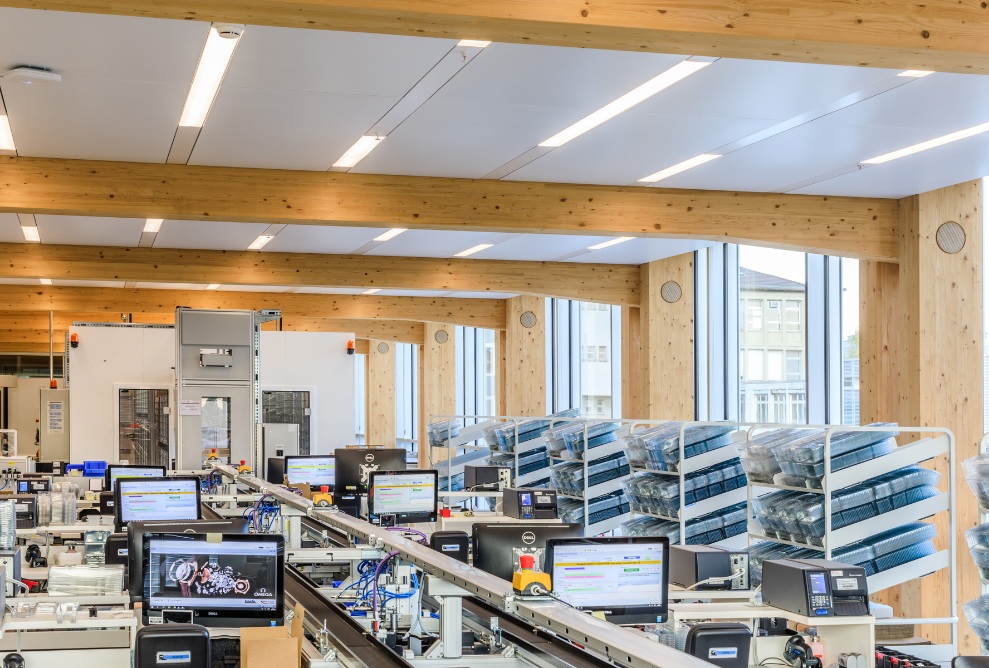 Prise de vue de l’atelier de production Omega avec structure de toit en bois et pièces ouvertes, lumineuses