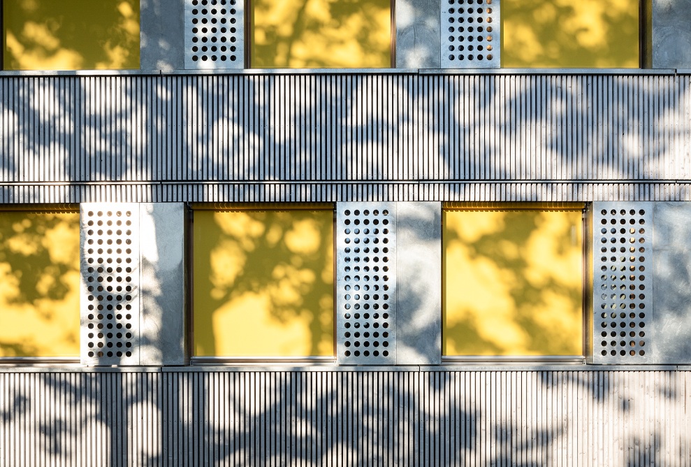 Façade en bois du pavillon scolaire de Brünnen avec stores jaunes