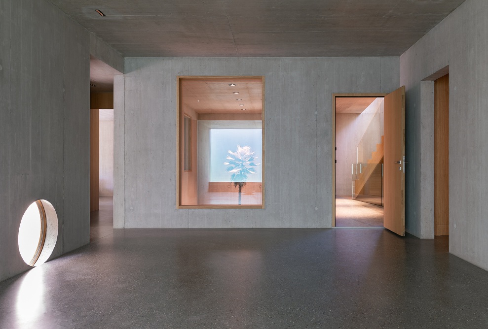 Space with concrete walls, wooden doors and large, unusually positioned windows in the semi-basement of Sutra House.