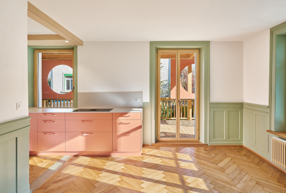 Kitchen in an accenting colour with wooden floor and green interior features