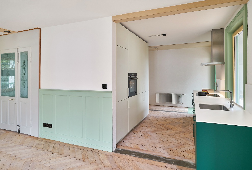 Open-plan kitchen and entrance area with green accenting features