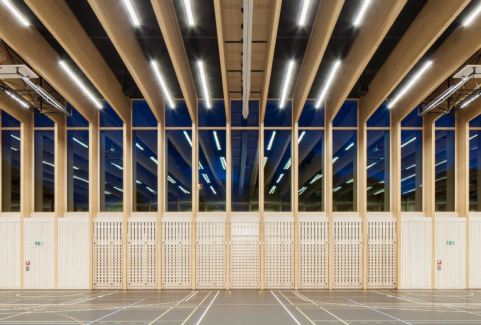 Photograph of the illuminated sports hall from the inside at dusk