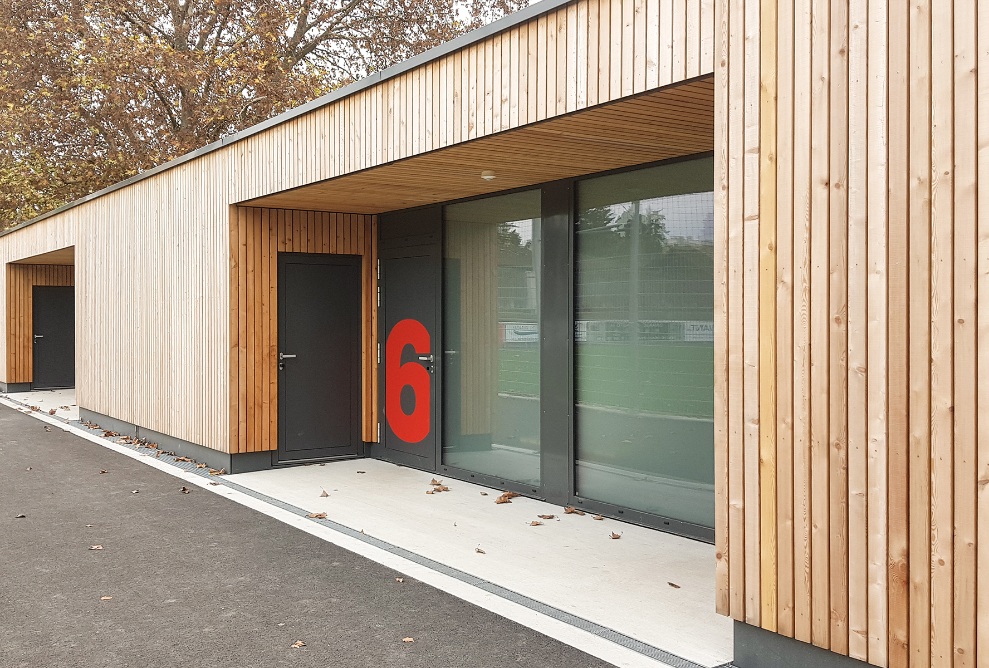 Striking lettering on the entrance to the changing rooms in the extension building with timber facade