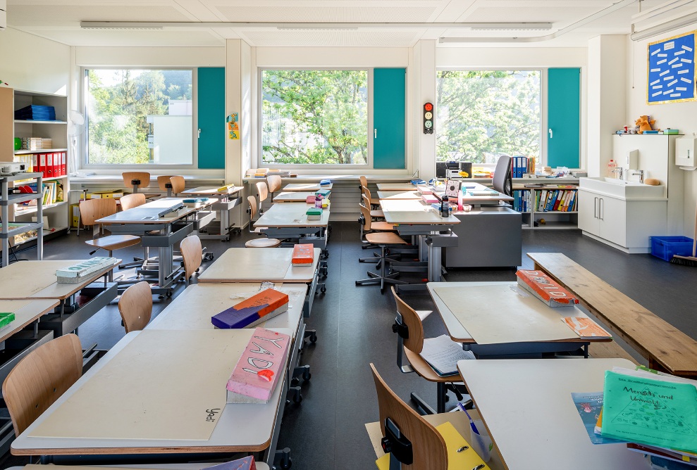 View of a classroom in the ZM10 Sihlweid school pavilion in Zurich with large windows in the background.